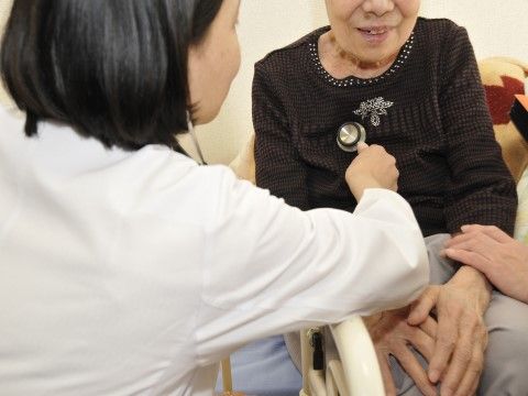 椅子に掛けて診察を受けるご年配の女性と聴診器を当てる女性医師