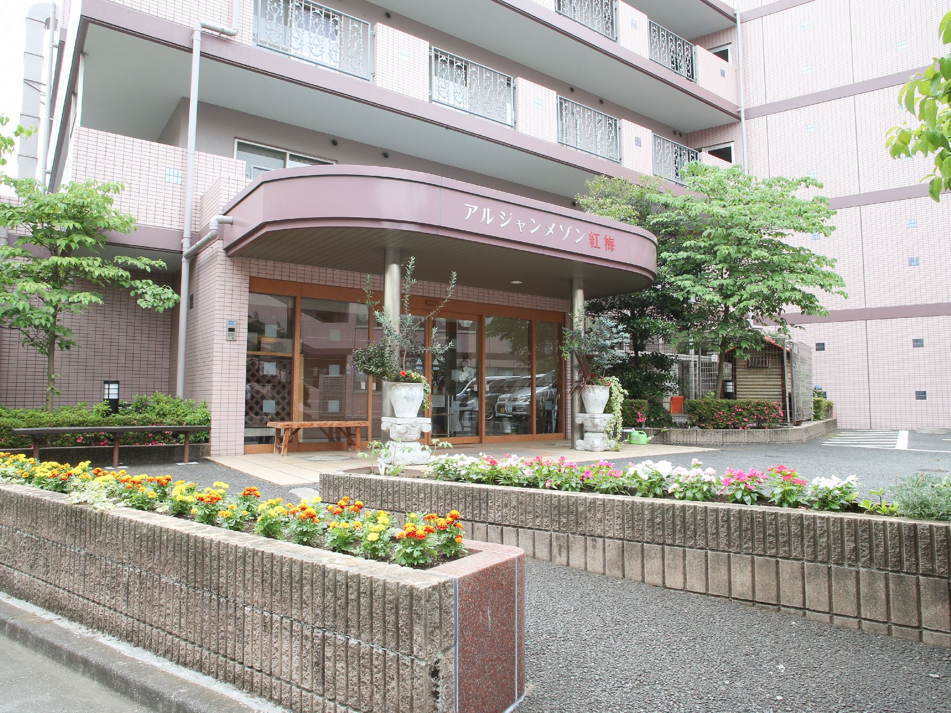 施設入口にはアルジャメゾン紅梅と施設名が表示されている。初めての方でも分かりやすい。花壇にはきれいな花がたくさん植えられている。