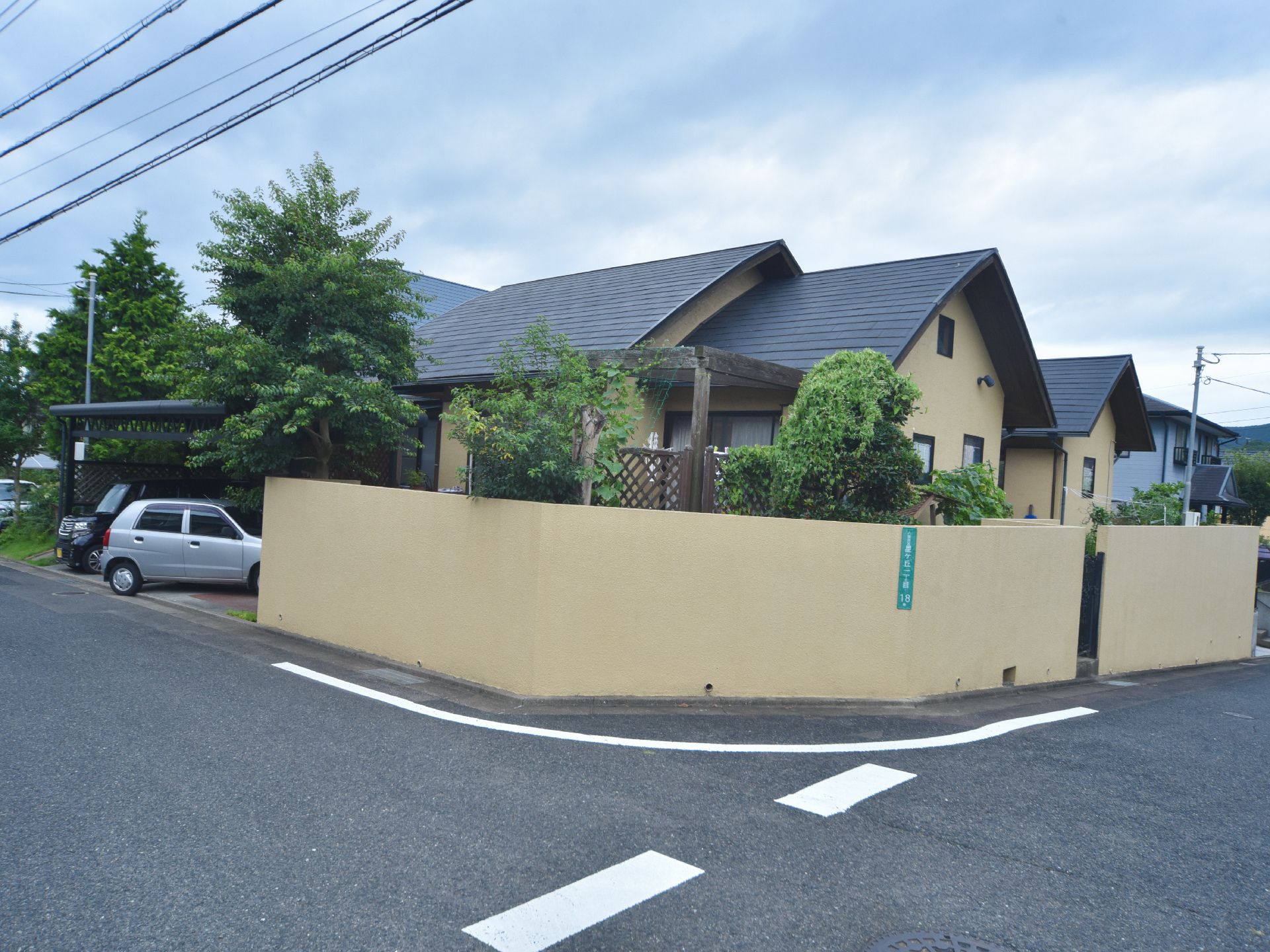 施設は道路の曲がり角部分に建っている。外周には建物の壁と同色の塀があり、内側には背の高い木が複数植えられている。