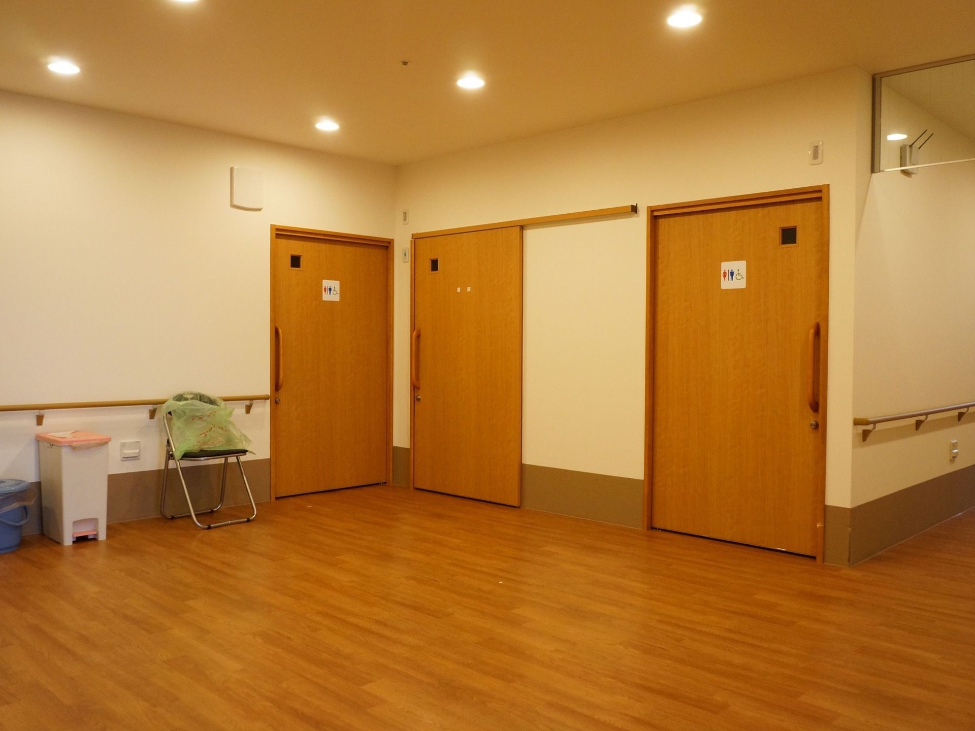 トイレ前には、ゆったりとしたスペースを設けている。壁に手すりを備え、天井に間隔を置いて小さめの照明を設置している。