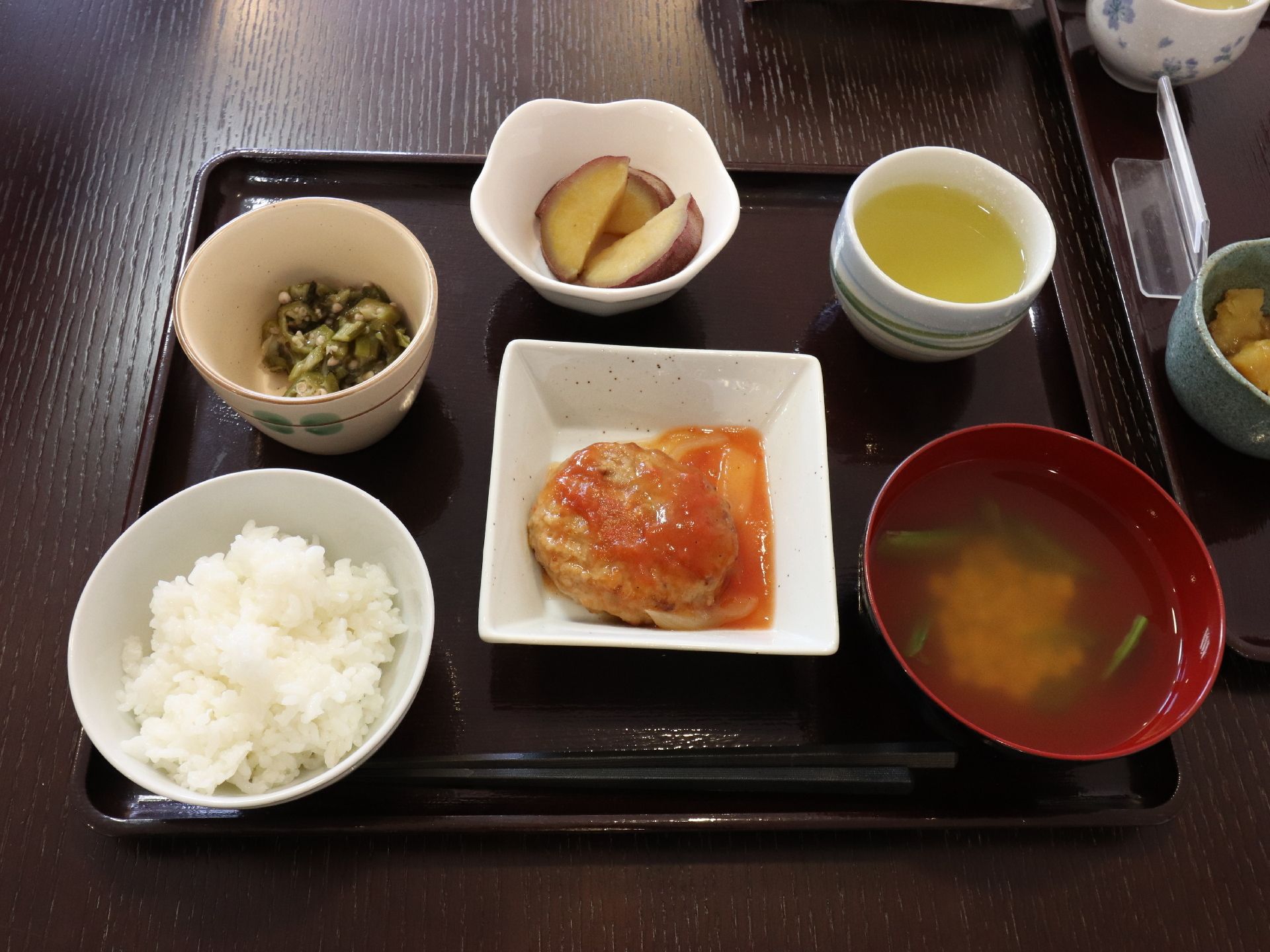 トマトソースのかかったハンバーグ定食になっている。白米、汁物、野菜のお漬物、サツマイモなど栄養バランスが考えられている。