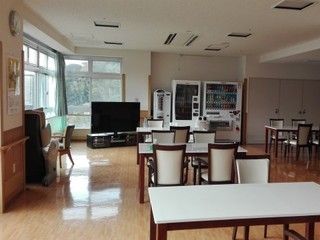 部屋の奥に自動販売機が2台設置された、白い机や椅子が並んだ共有スペース