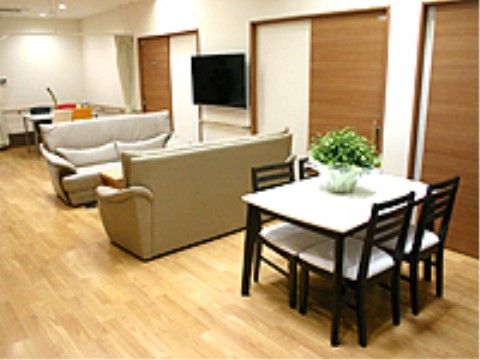フローリングの室内にソファーやテーブルセットが置かれている。壁にはテレビが掛けられており、引き戸が3ヶ所設置されている。