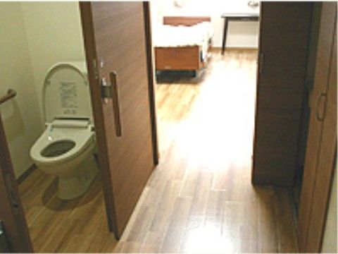 床はすべて木目調になっている。廊下をはさんで収納スペースとトイレが向かい合っており、トイレ内には手すりが設置されている。