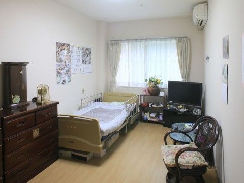 介護用ベッドとテレビや箪笥がある、花瓶の飾られた居室