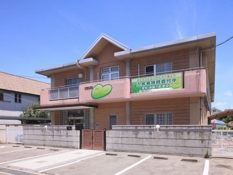ピンク色のベランダがある、ブロック塀で覆われた施設外観