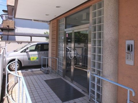 入口はガラス扉になっていて、手すりが取り付けられている。地面はタイル張りで、頭上には屋根が設置されている。