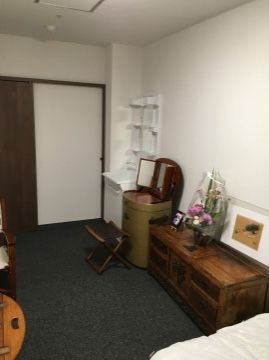 居室の入り口には、重厚な木目調の横開きドアがついている。部屋の中には、洗面台、鏡台、チェストなどの家具が並ぶ。
