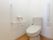 共有スペースのトイレのトイレは、壁面に固定のほか、可動式の手すりを設けて両側は支えられるようにした。非常呼び出しボタンも付いて安心。