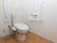 居室のトイレはウォシュレット水洗トイレ。壁にはL字型の手すりと呼び出しスイッチがある。便器の横にも可動式の手すりがあり上下に動かせる。