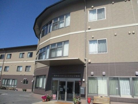 丸みを帯びた外観で、入口付近にベンチや鉢が並べられた、施設の玄関