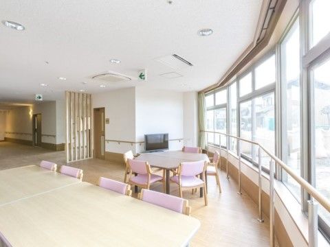 たくさんの大きな窓があり、窓辺に多角形のテーブルがある共有スペース