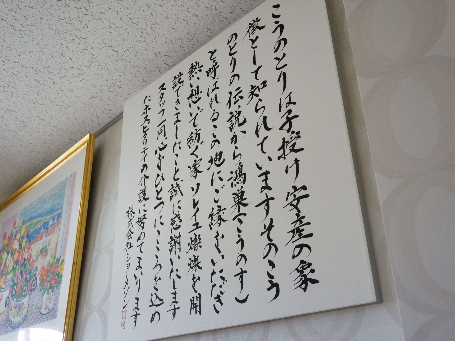 丸い模様の入った壁に筆文字で書かれた掲示物がある。入居者様に対する施設のスタッフからの言葉になっている。
