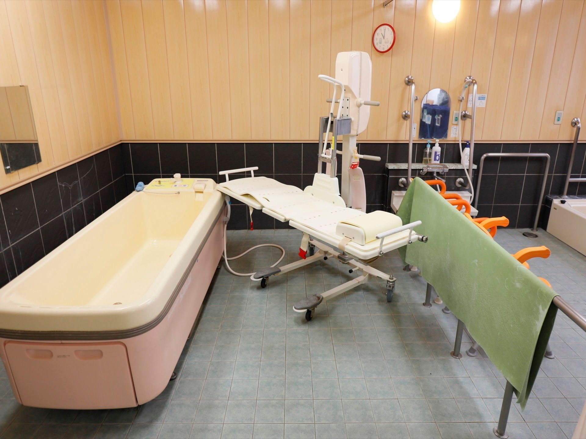 寝たままの姿勢でお湯につかっていただける介助入浴の設備がある。ひじ掛けのついた椅子も４つ置かれている。