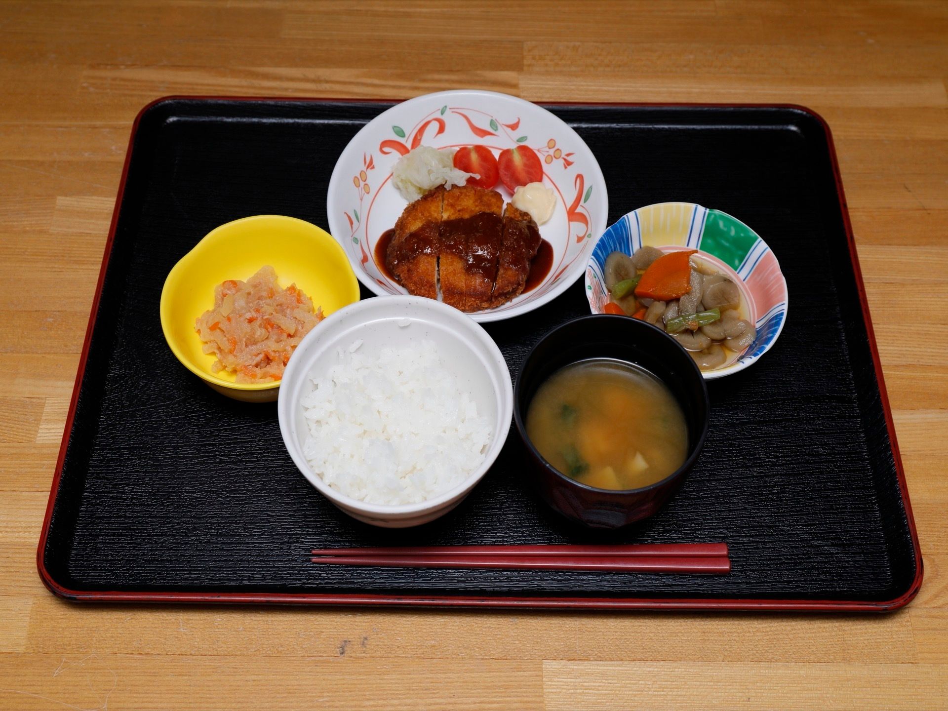 お盆に食事がのっている。ご飯、みそ汁のほか、野菜やお肉も使ったおかずが３種類ある。おかずは小鉢に分けて置かれている。