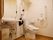 洗浄暖房便座のトイレがある。便座に座って右側には広いスペースがある。大きな手すりやナースコールボタンが設置されている。