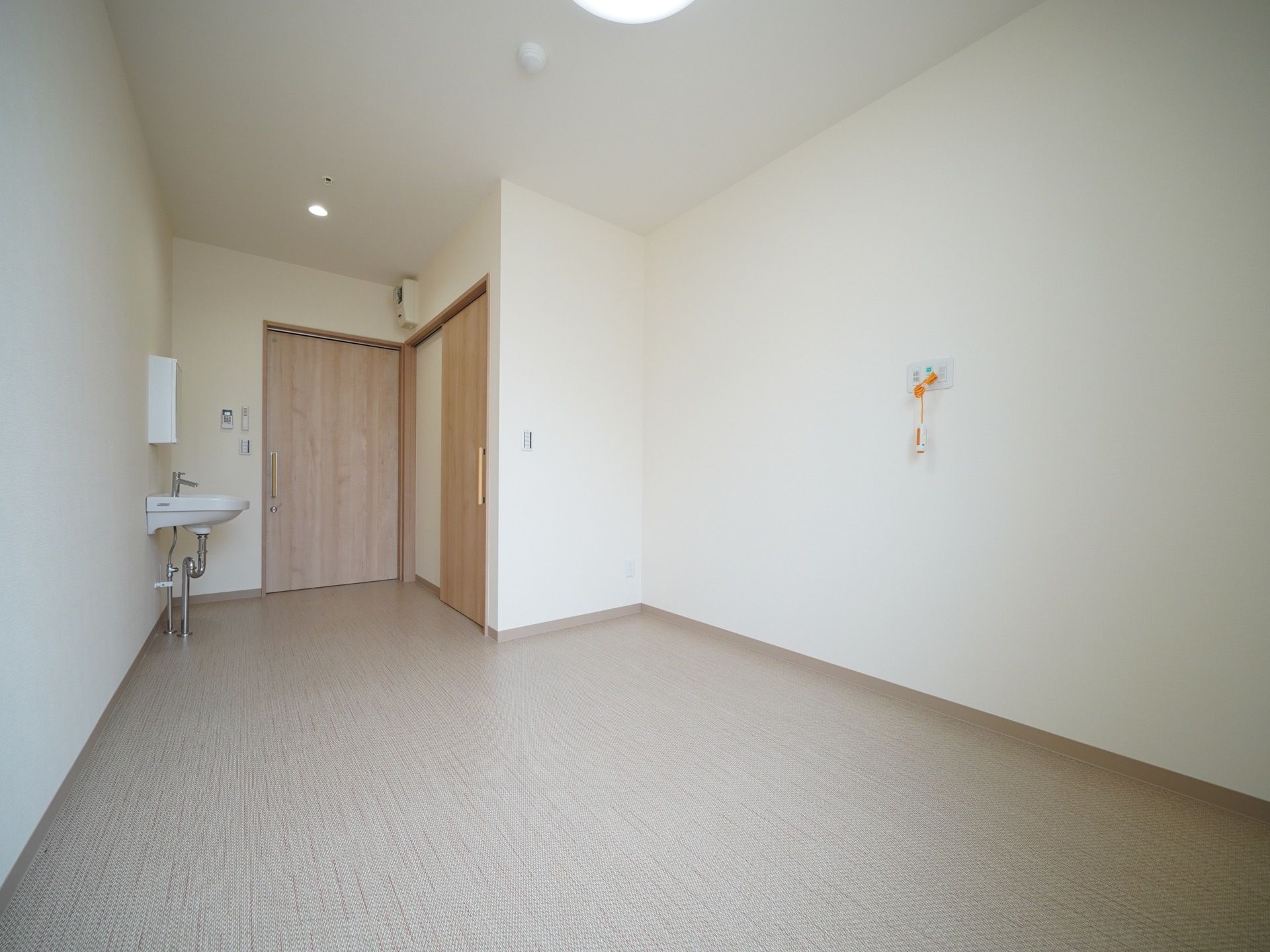 居室内はドアの横にトイレがあり、その向かいに洗面台がある。ほぼ長方形の間取りで壁にナースコールが取りつけられている。