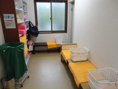 脱衣ベンチの上には大きな黄色いバスタオルが敷かれている。入居者様が脱衣を入れるための白いカゴが用意されている。