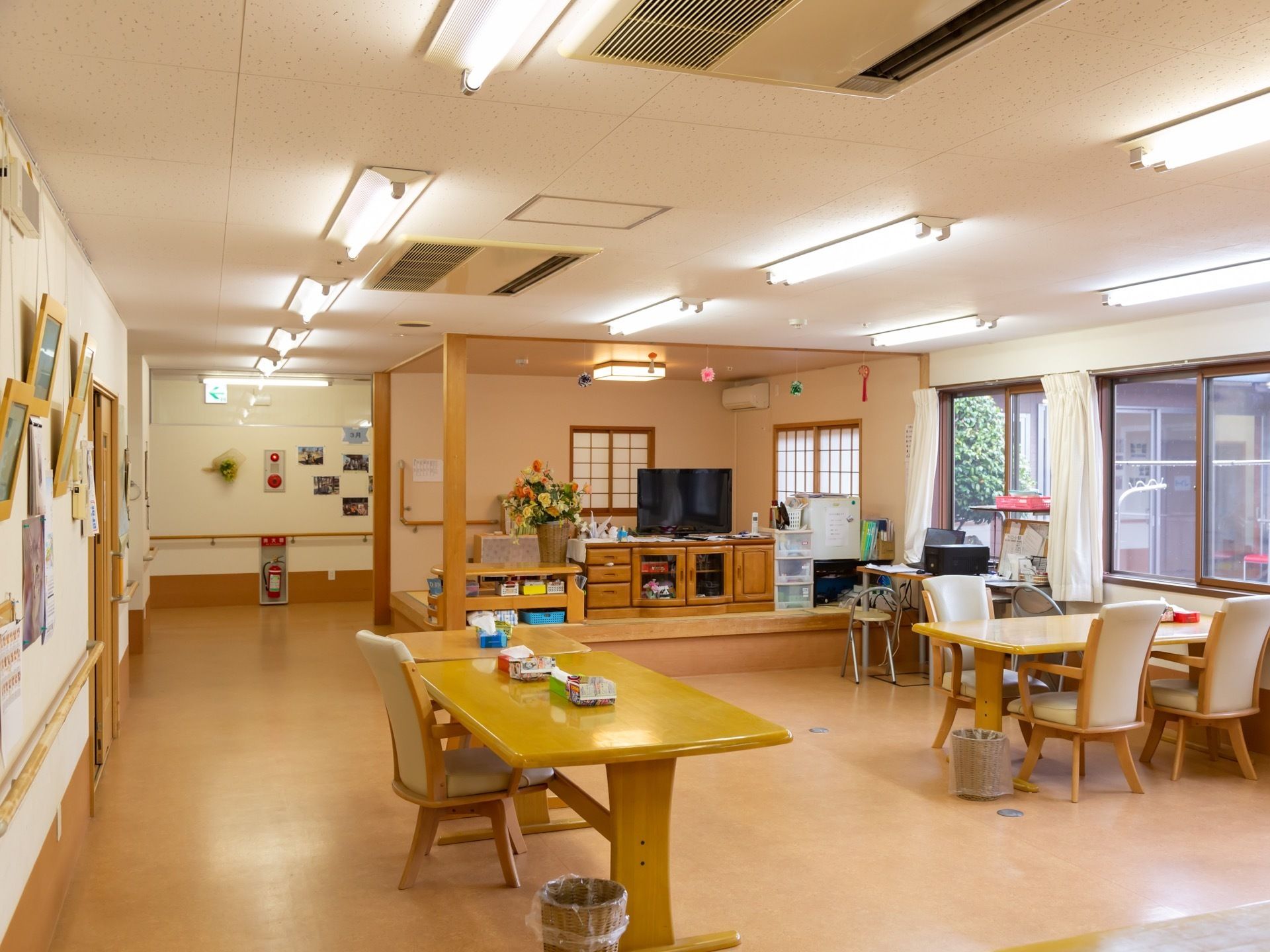 複数の椅子や机を用意している。大きいサイズのテレビが一つある。空調機も複数設備されている。照明が明るい。