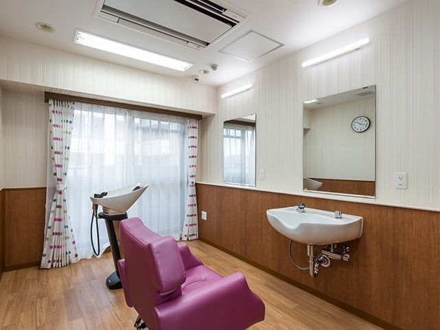 鏡が二面あり、うつむき用と上向き用のシャワー台がそれぞれ１台ある。紫色のリクライニングチェアが１脚ある。窓があり室内は明るい。