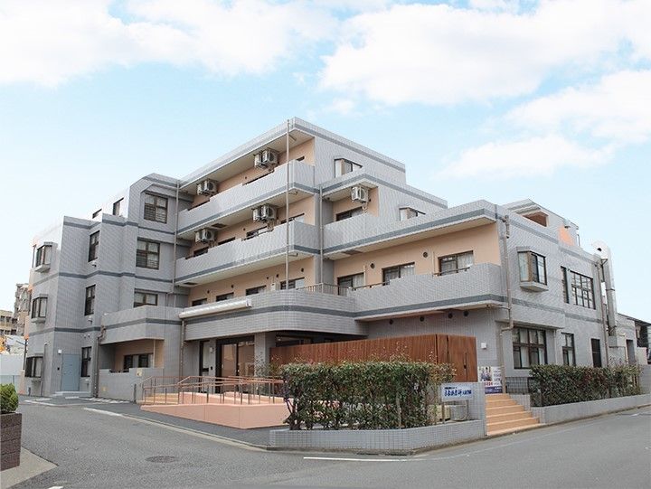 目隠しで覆われた1階のデッキテラスを持つ、マンションの様な施設外観