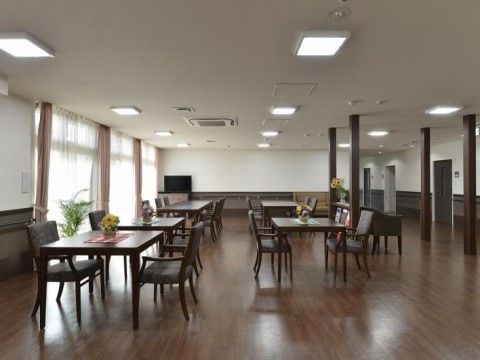こげ茶を基調としたシックな印象のリビングである。デザイン性のあるテーブルセットがゆったりと配置されている。