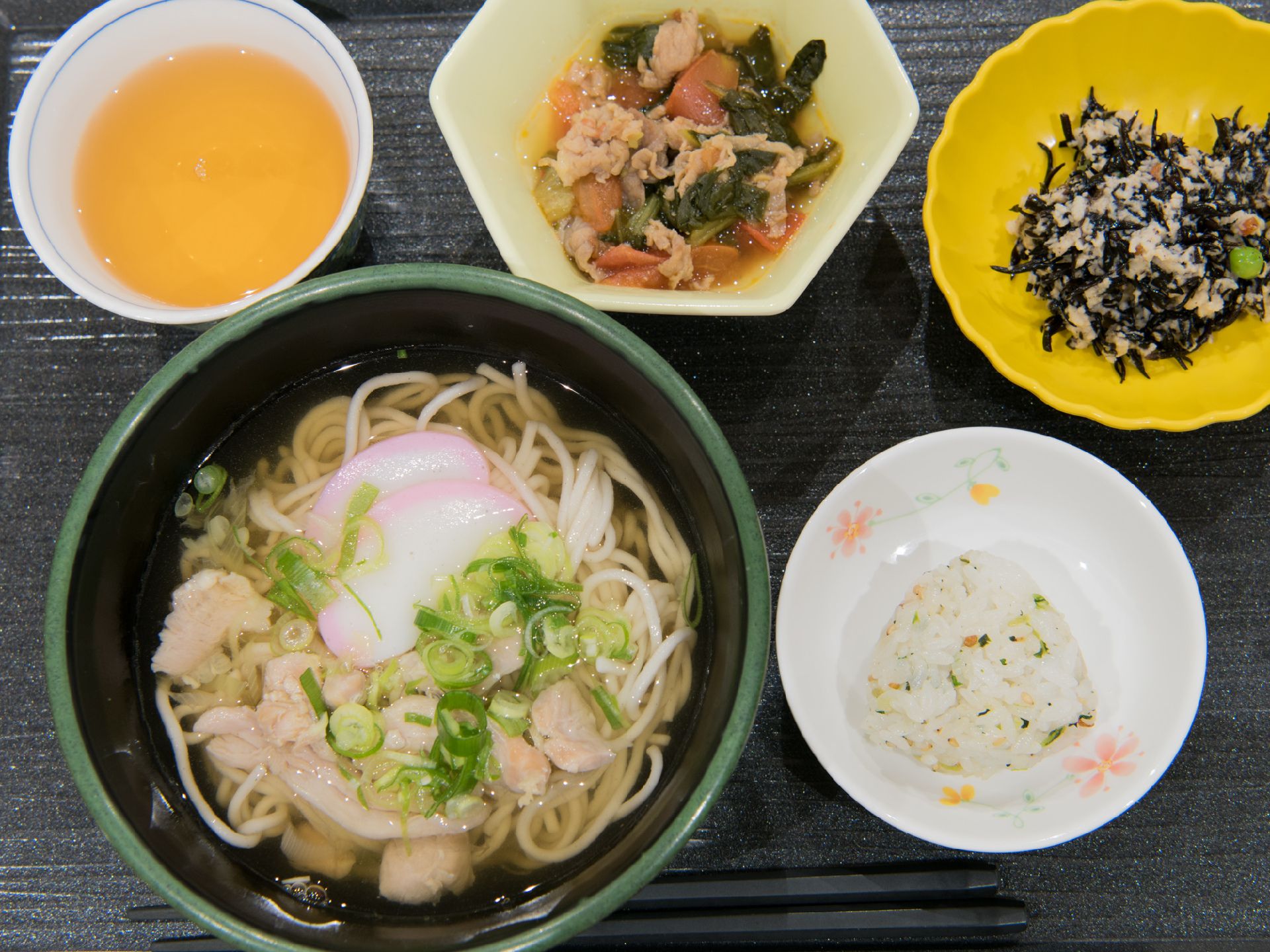 この日の食事の主菜は、うどんである。副菜は、にんじんなど野菜の煮物と、ひじきの煮物の2品ついている。