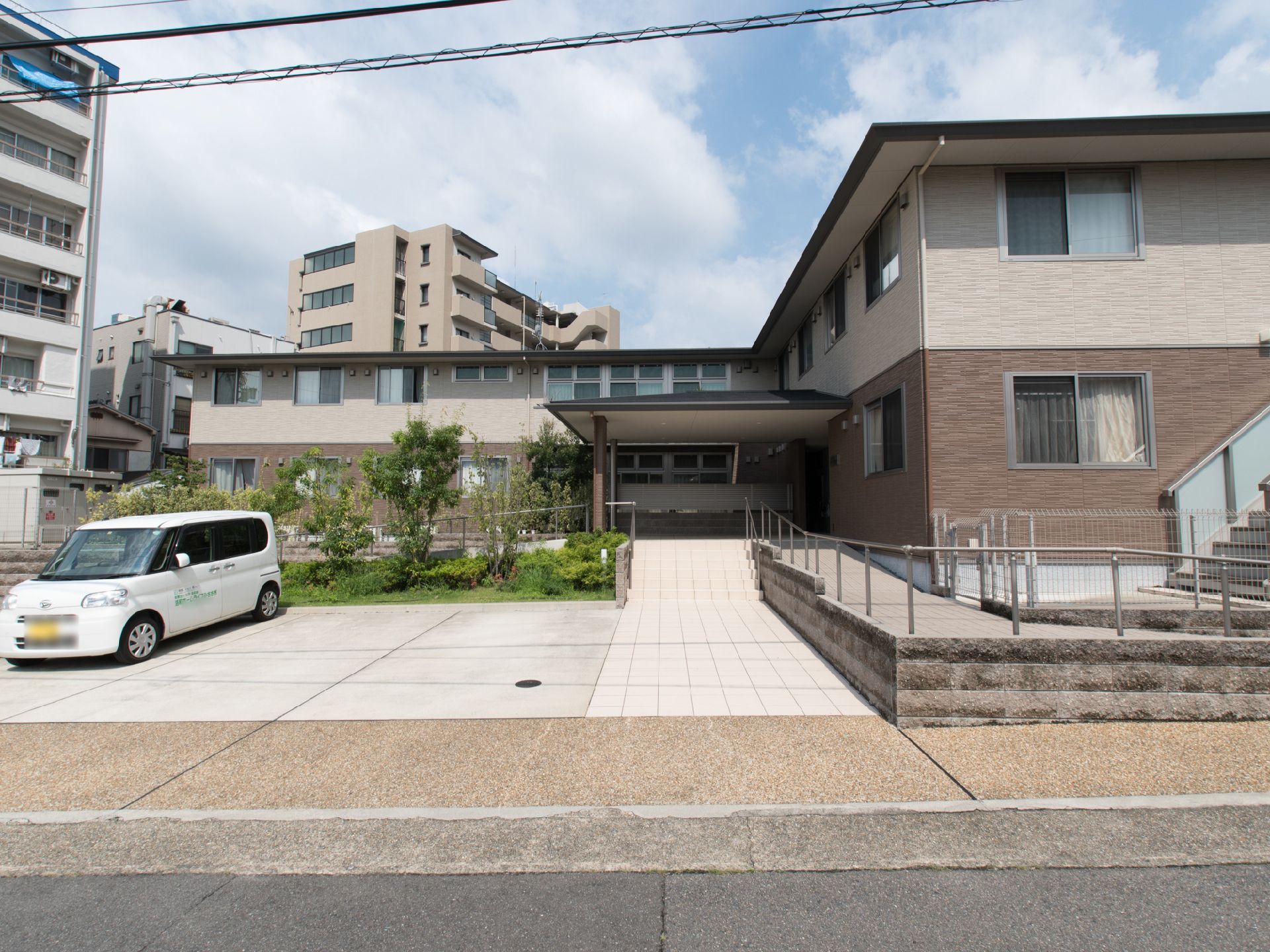エントランスまでは、階段かスロープを利用する。両方とも手すりが設置されているので安心である。敷地内には植栽が植えられている。