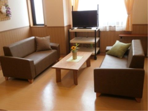 机を挟んでソファーが置いてある。テレビが設置されている。広々としており、入居者様はくつろいで過ごすことができる。