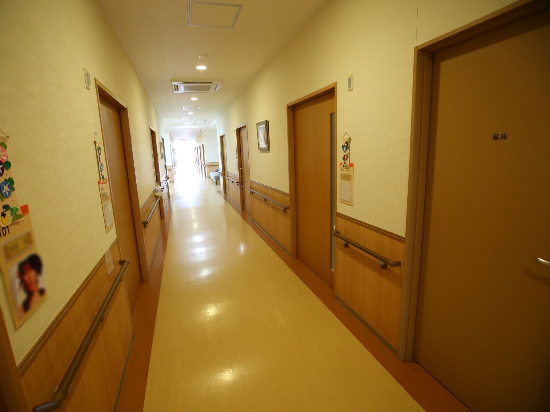 通路の床の中央は白く、両端は茶色になっている。両側の壁には手すりが設置されており、茶色のドアが並んでいる。