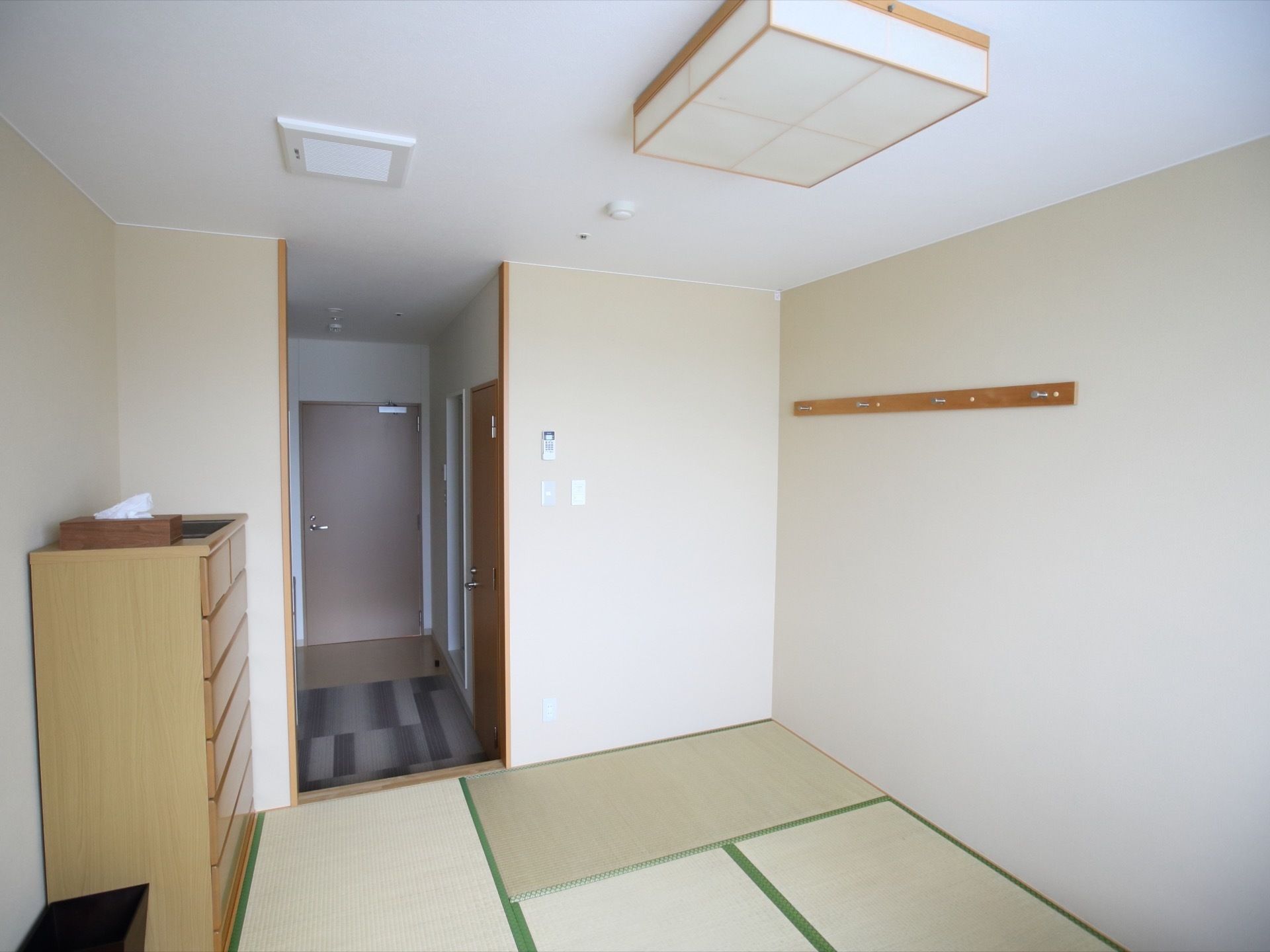 畳が敷かれた和室のゲストルームである。左側にはタンスが置かれており、天井には和風の照明がある。