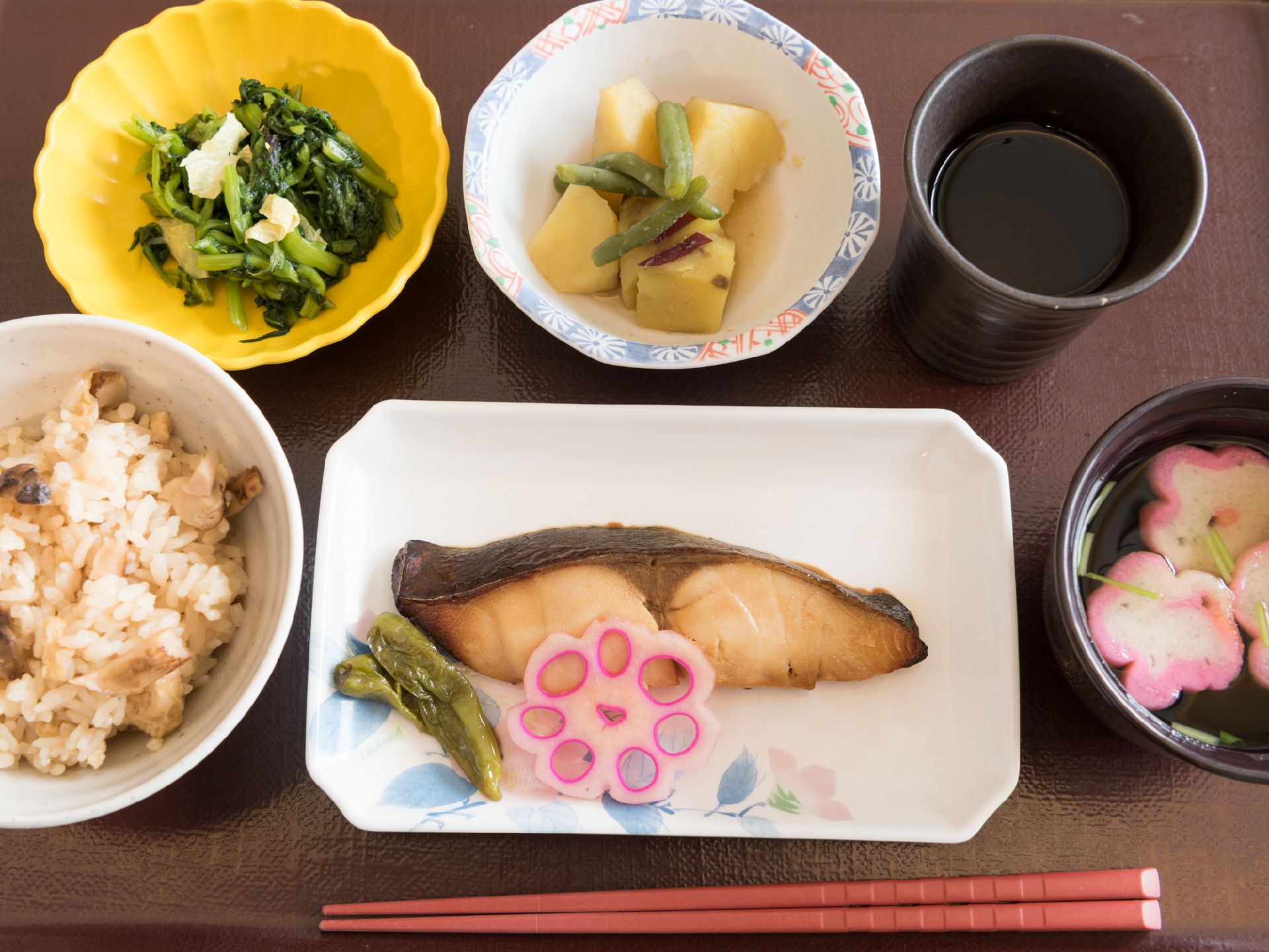 トレーに食事が載っている。炊き込み御飯と吸い物に主菜、副菜二品で野菜が多く、バランスのとれた食事である。