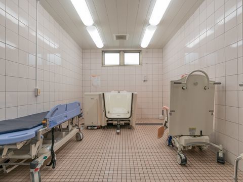 介護用の浴室で、横になったり座ったりしたまま入浴できる装置のついた浴槽やストレッチャーが置かれている。