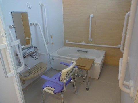 浴室内の壁や浴槽内にも多くの手すりが取り付けられた浴室。浴槽には縁をまたがなくても済む移乗台が設置されている。
