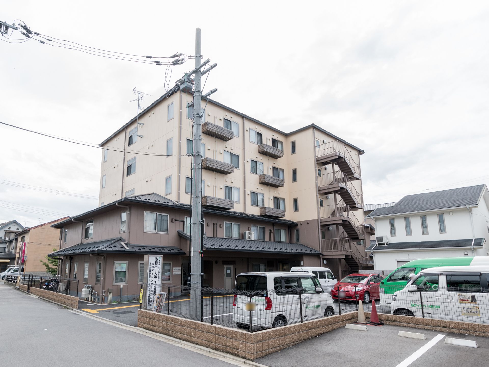 一軒家とマンションが合わさったような形をしている建物である。5階建てで、手前に駐車場が整備されている。