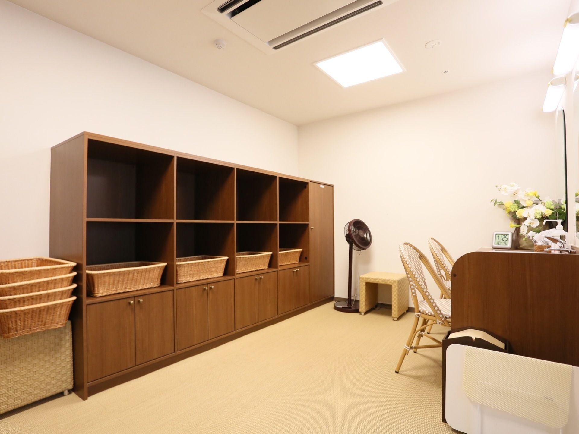 脱衣所には椅子が並べられている。その後ろには扇風機と棚があり、脱ぎ着する服を入れる籠が置かれている。
