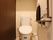 トイレには、洗浄機能付き便座が設置されている。壁面の上部には収納棚が付いており、側面には手すりと非常用コールボタンが取り付けられている。
