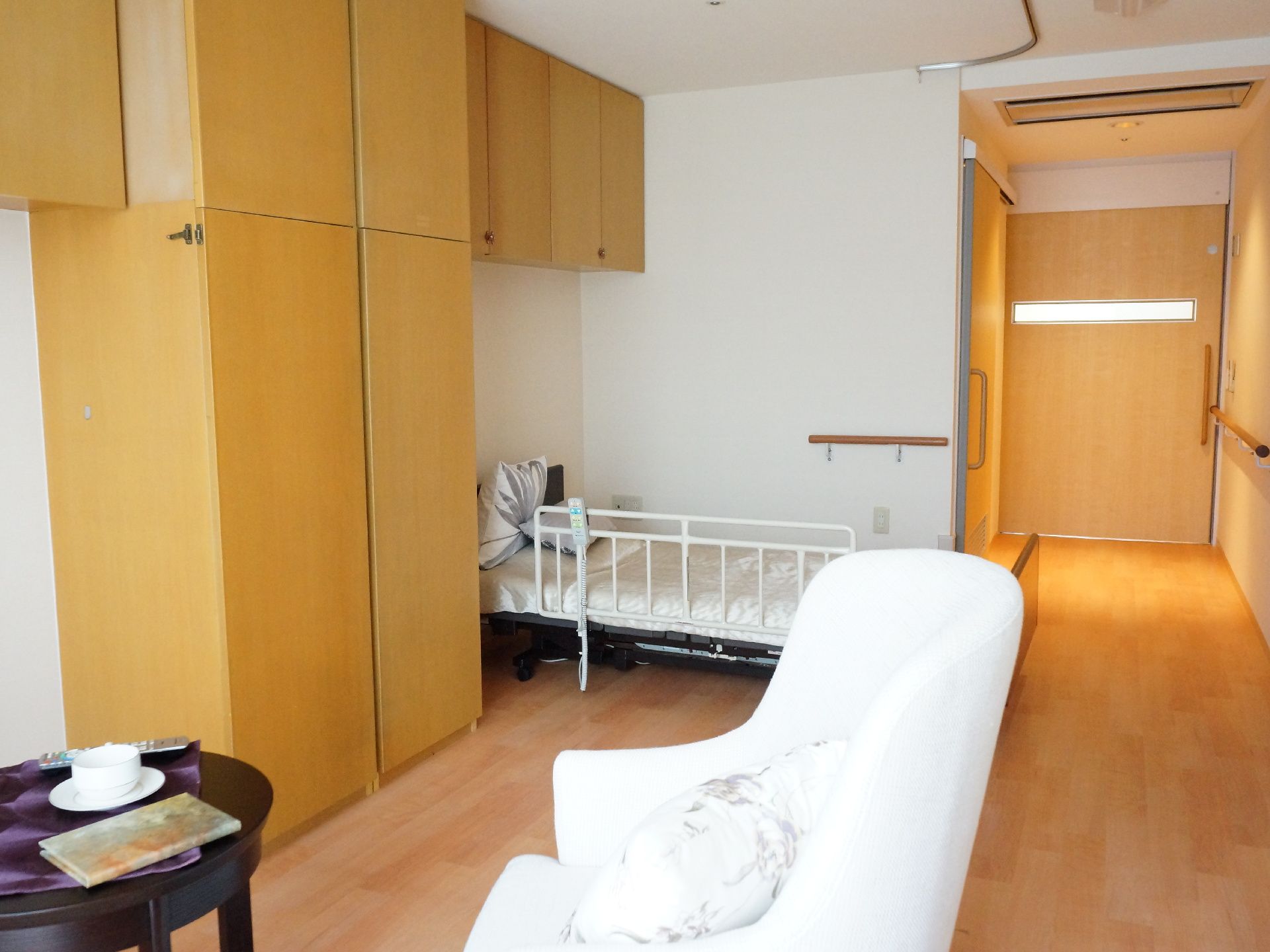 壁面に大きなメインの収納がある。他にもテレビの上やベッドの上にも複数収納がついている。収納を挟んで、寝室エリアとリビングエリアを分けている。