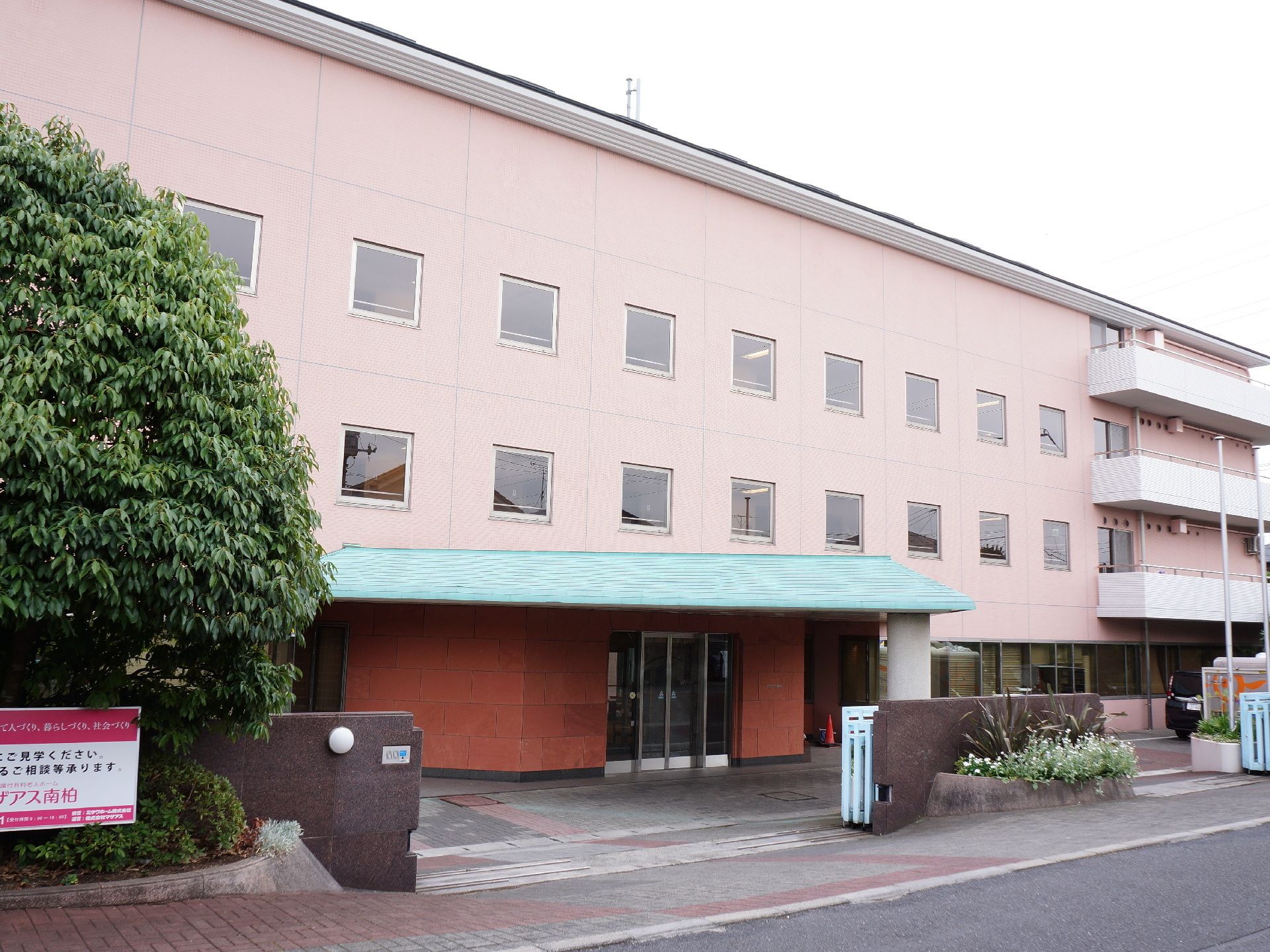 伸縮門扉が隣接する道路への出入り口に設置されている。正面に玄関。建物は5階建て。玄関前には大きい屋根がついており便利。