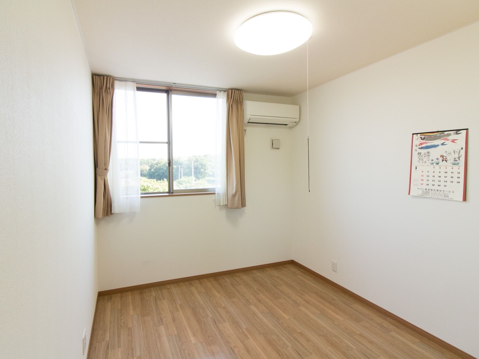 窓がある明るい居室である。外の景色は緑が多く、お部屋でゆったりとくつろぐことができる。自然に触れることができる環境である。