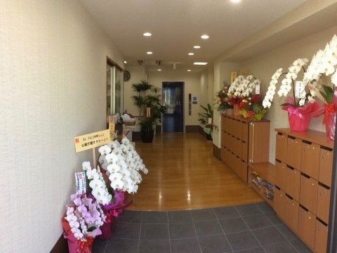 玄関には多くの花や観葉植物が飾られている。下駄箱は来訪者様用のものもあり、多人数での訪問の際も対応できる。