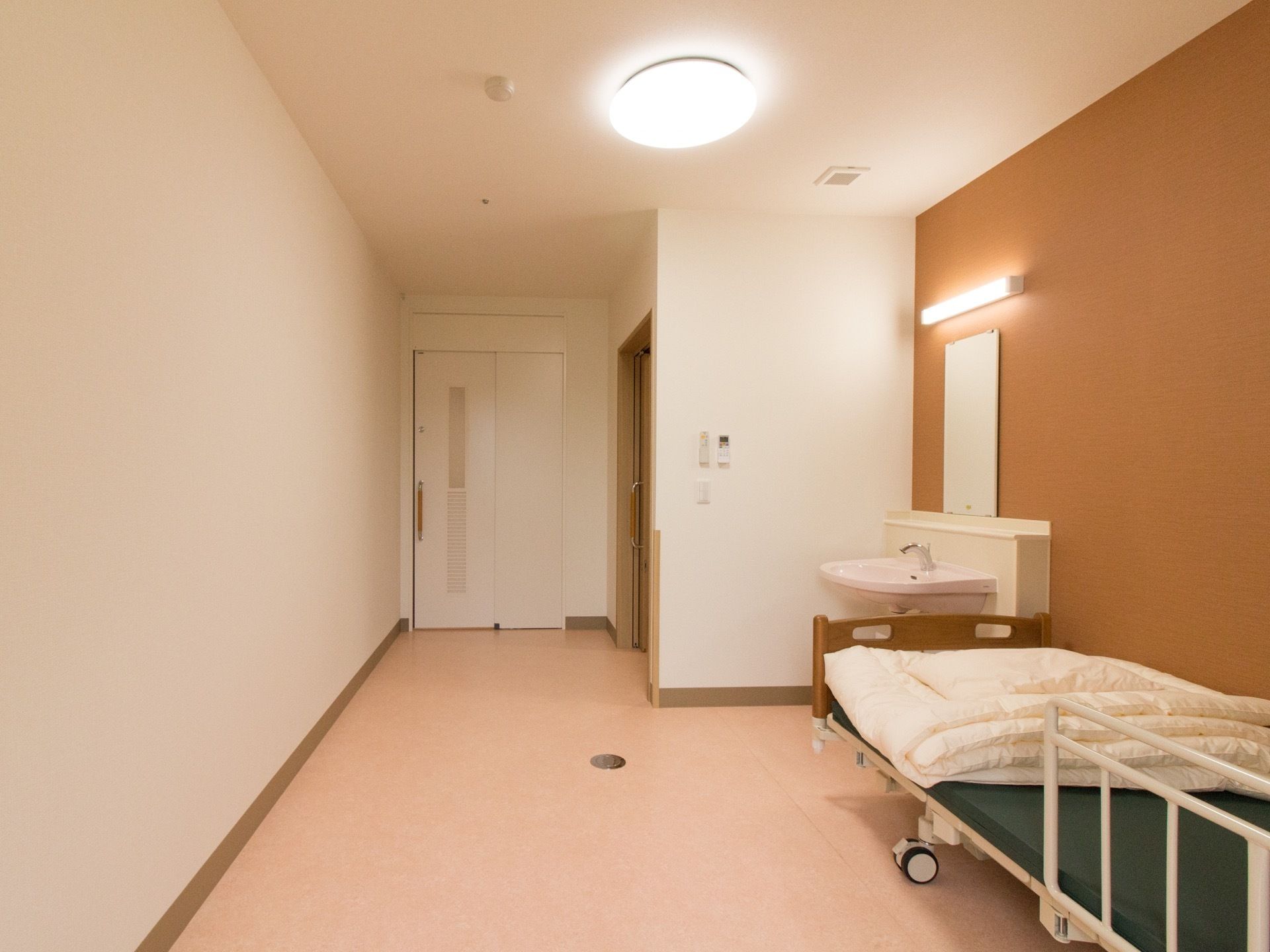 白を基調としたシンプルな居室に、アクセントクロスが淡いブラウンが温かみを与えている。ベッド、洗面台、トイレを完備している。