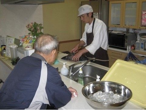 スタッフが魚をさばいている様子を間近で見守るご入居者様