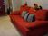 居室の中に赤い大きめのソファが置かれている。ストライプのクッションが3つある。玄関には消火器が用意されている。
