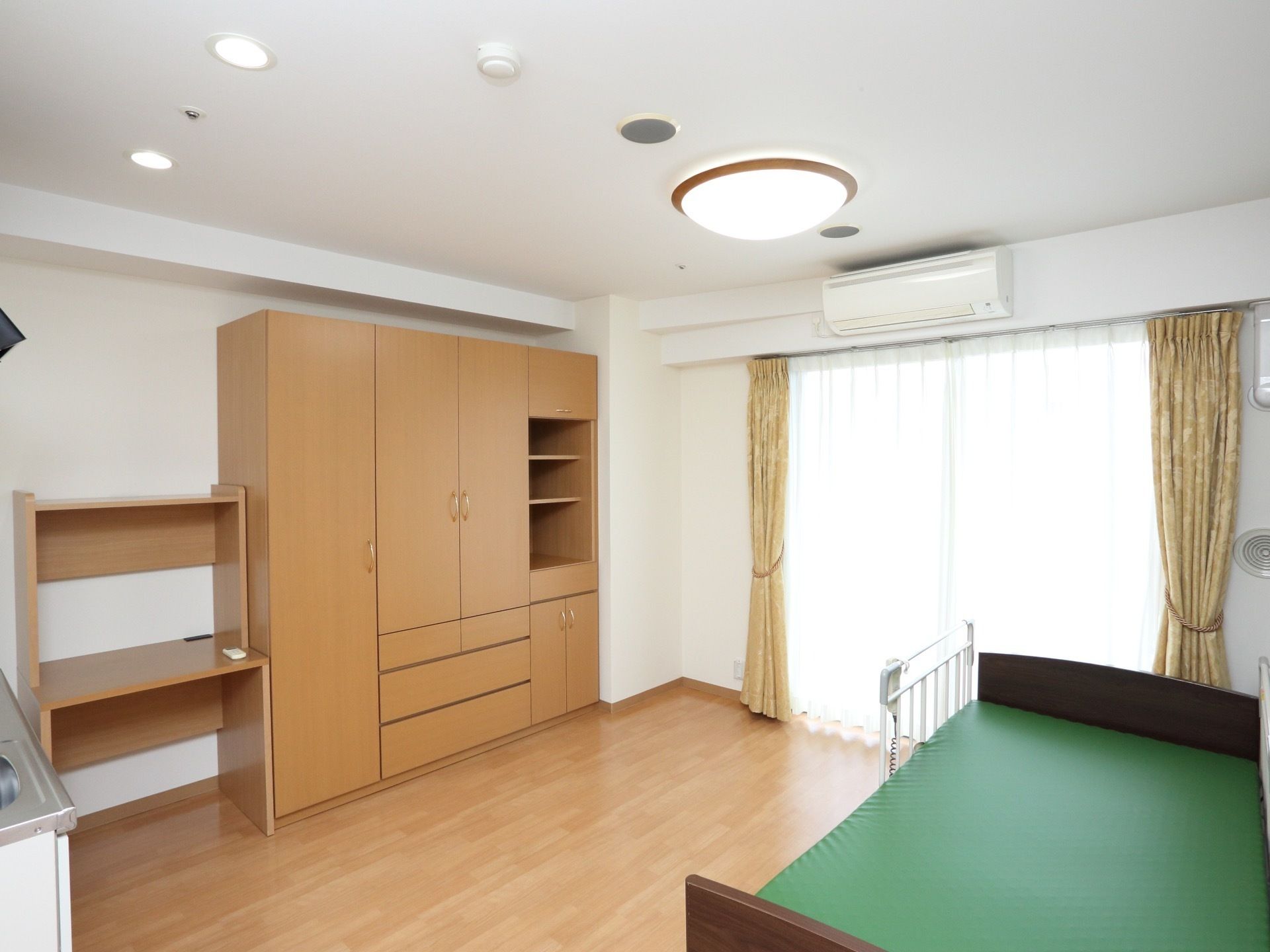 個室の部屋には収納や机、電動ベッドに照明、エアコンと充実の設備が備え付けられている。特別な用意がなくても入居後、生活ができる。