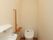 奥行きのあるトイレは、左側に簡易手洗い場と長い棚が設置されている。縦向きの手すりも取り付けられている。