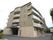 ５階建てのマンションのような外見の建物で、１階部分はベージュ色のレンガ風の壁になっている。玄関の前にはひさしが付いている。