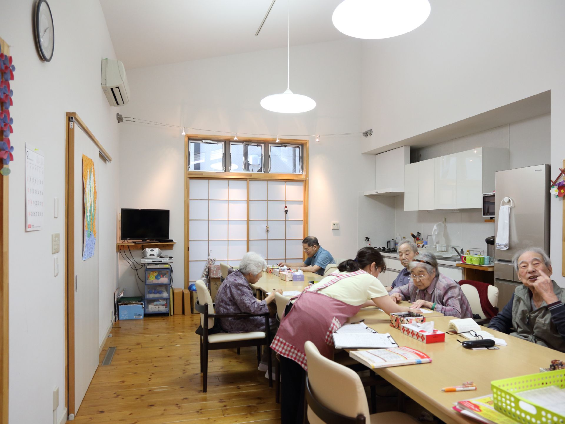 天井が高い白い壁のお部屋で、キッチンや冷蔵庫が設置されている。テレビやラジカセもあり、レクリエーションを行うことができるスペースである。