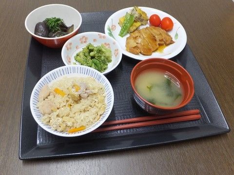 炊き込みご飯や鶏肉、野菜を使った副菜のあしらわれた食事