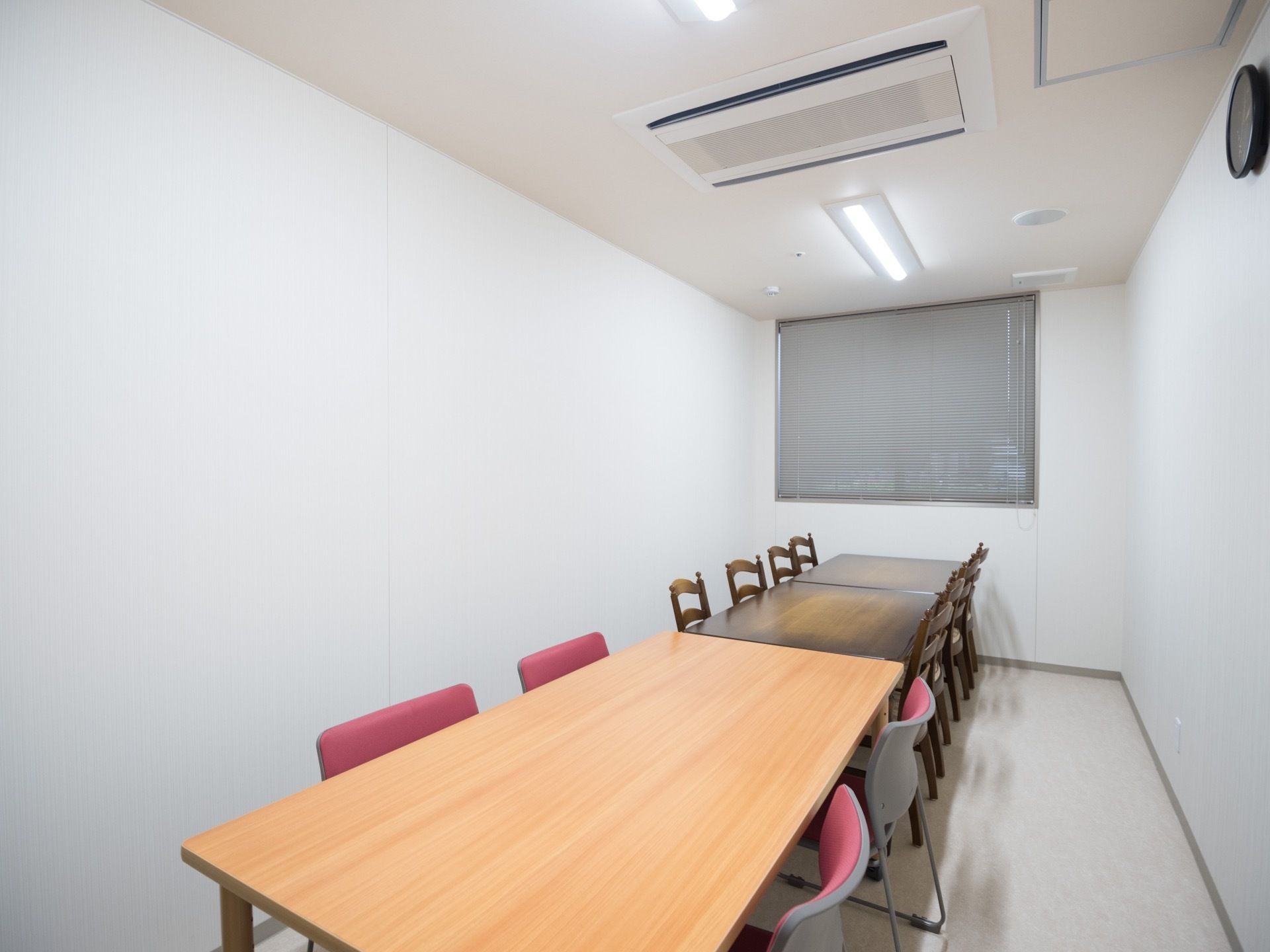 空調設備が整った個室の相談室である。天井には蛍光灯が２つ設置されており、壁には時計が掛けられている。